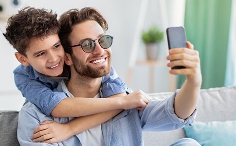 Father and son smiling while taking a selfie.